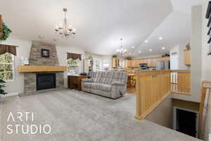 Living room featuring an inviting chandelier, lofted ceiling, recessed lighting, a fireplace, and light colored carpet