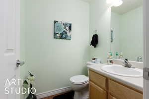 Half bathroom featuring toilet, vanity, and baseboards