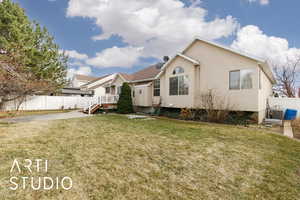 View of front of property featuring stucco siding, a front yard, and fence