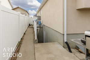 View of side of property featuring stucco siding and fence