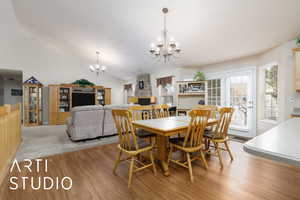 Dining space featuring a chandelier, light wood-style flooring, and lofted ceiling