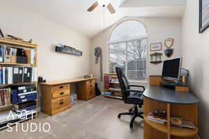 Home office featuring carpet, a ceiling fan, and vaulted ceiling