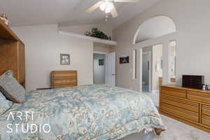 Bedroom featuring ceiling fan, ensuite bathroom, and vaulted ceiling