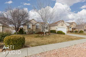 View of front of property featuring a front lawn, concrete driveway, a garage, stone siding, and a residential view