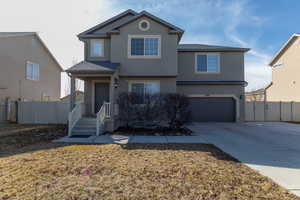 Traditional-style house with stucco siding, concrete driveway, an attached garage, and fence