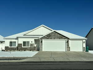 This photo is an example of an exteior view of the home View of front of house with a garage, stone siding, board and batten siding, and driveway