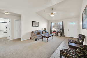 Carpeted living room with lofted ceiling, baseboards, and ceiling fan