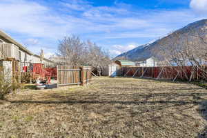 View of yard with an outbuilding, a shed, a mountain view, and a fenced backyard