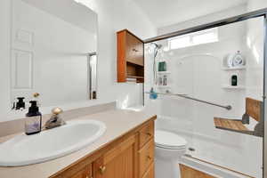 Bathroom featuring vanity, toilet, and a stall shower