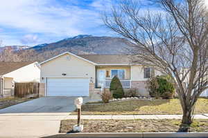 Single story home featuring brick siding, a mountain view, concrete driveway, and an attached garage