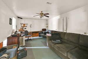 Living area featuring radiator heating unit, a ceiling fan, visible vents, and concrete floors