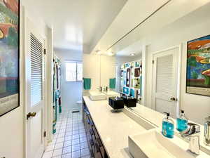 Full bathroom with double vanity, tile patterned flooring, toilet, and a sink