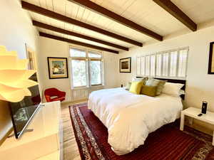 Bedroom with beamed ceiling, wood ceiling, and light wood-style flooring