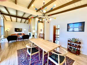 Dining space featuring beamed ceiling, a notable chandelier, wood ceiling, and light wood-type flooring