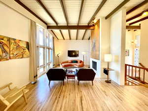 Living area with beam ceiling, a fireplace, an inviting chandelier, and wood finished floors