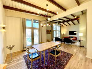 Dining space featuring an inviting chandelier, vaulted ceiling with beams, french doors, and light wood finished floors