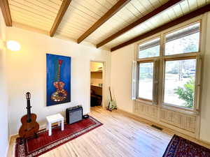 Living area with lofted ceiling with beams, wood finished floors, visible vents, and wooden ceiling