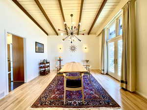 Dining room featuring beam ceiling, french doors, an inviting chandelier, and wood finished floors