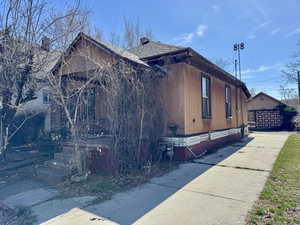 View of home's exterior featuring roof with shingles, concrete driveway, and a chimney