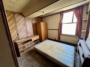 Unfurnished bedroom featuring wood walls