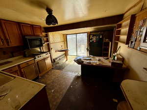 Kitchen with baseboard heating, black appliances, and open shelves