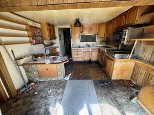 Kitchen with light countertops, brown cabinets, and open shelves