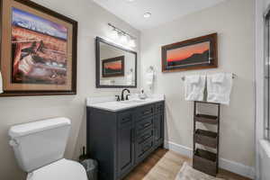 Bathroom featuring baseboards, toilet, wood finished floors, and vanity