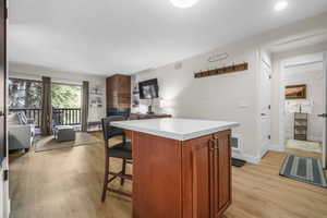 Kitchen with a kitchen bar, open floor plan, a center island, light wood-style floors, and light countertops