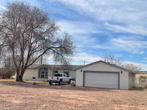 View of front of home featuring an attached garage and dirt driveway