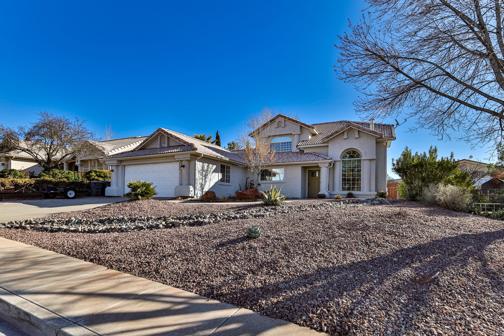 View of front of house with a tiled roof, a garage, driveway, and stucco siding