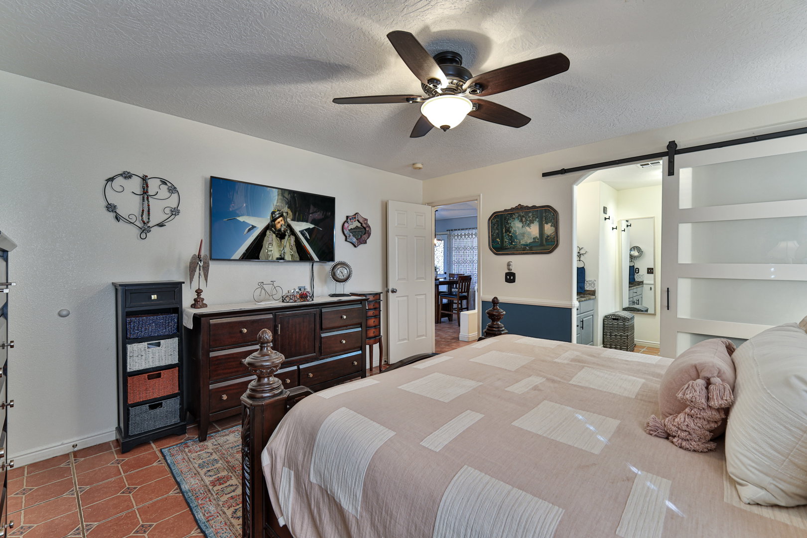 Bedroom with tile patterned flooring, ceiling fan, a textured ceiling, and a barn door