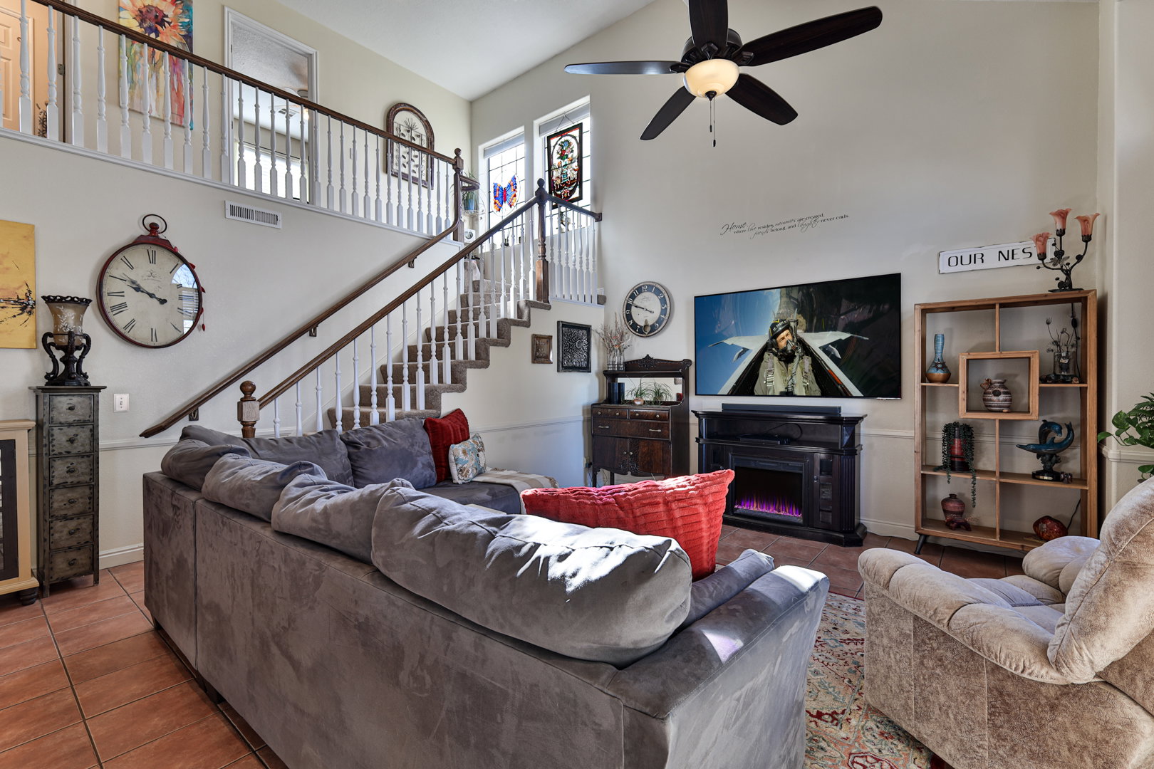 Living area with visible vents, stairs, a towering ceiling, tile patterned floors, and a glass covered fireplace