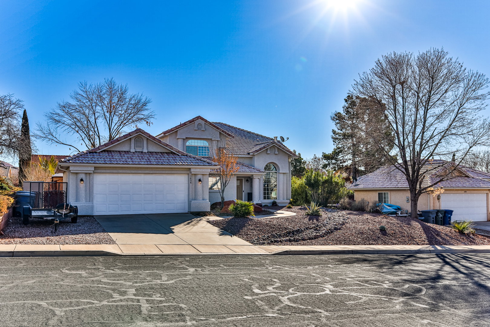 View of front of home featuring a garage, driveway, stucco siding, and a tile roof