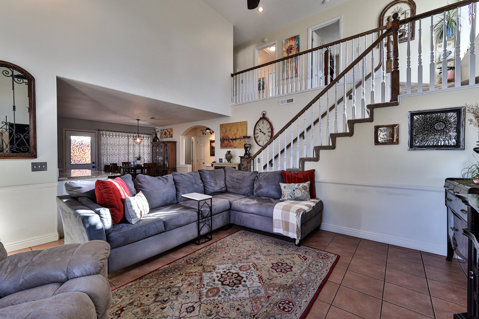 Living room featuring visible vents, stairway, arched walkways, tile patterned flooring, and baseboards