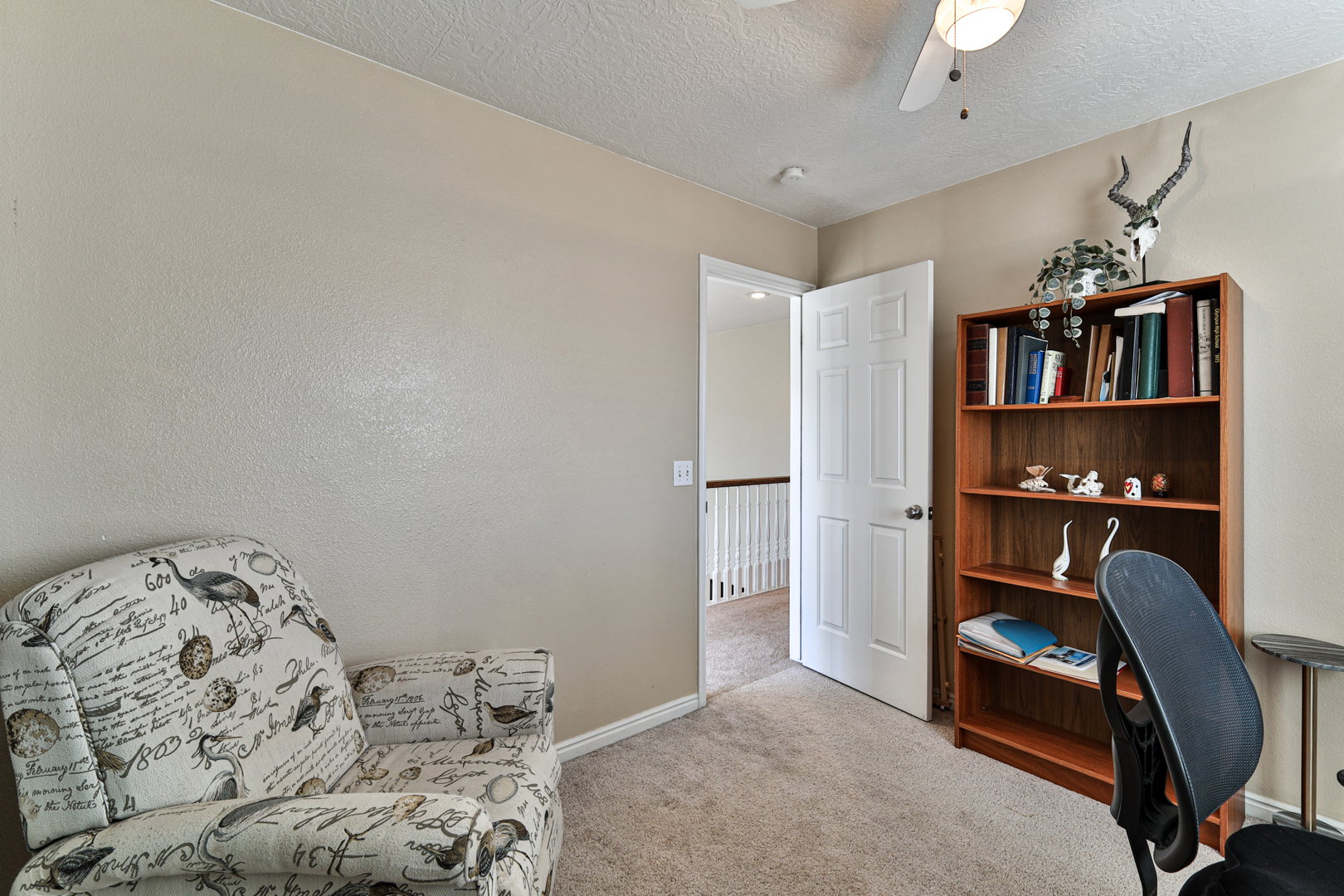 Carpeted office featuring baseboards, a textured ceiling, and a ceiling fan