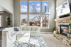 Carpeted living area featuring baseboards, arched walkways, a towering ceiling, and a fireplace