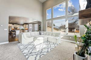 Living room with baseboards, a high ceiling, recessed lighting, arched walkways, and a chandelier