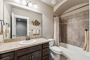 Bathroom with visible vents, toilet, vanity, and shower / tub combo with curtain