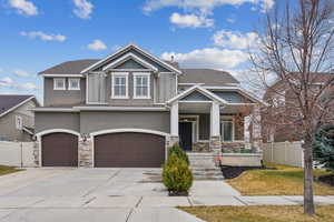 Craftsman-style house with fence, a porch, stucco siding, stone siding, and driveway