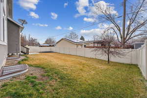 View of yard featuring entry steps and a fenced backyard