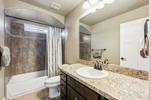 Bathroom with visible vents, shower / bath combo with shower curtain, toilet, and vanity