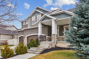 Craftsman house featuring stucco siding, stone siding, covered porch, and a gate