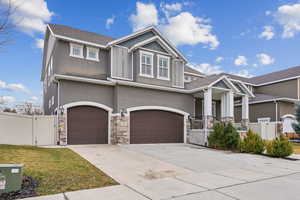 Craftsman inspired home with stone siding, fence, driveway, and a gate