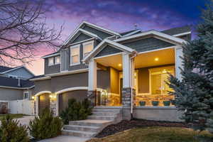 Craftsman-style house with a gate, driveway, an attached garage, covered porch, and stucco siding