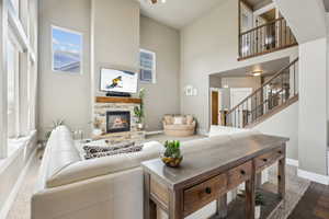 Living area with stairway, a fireplace, baseboards, and a towering ceiling