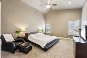 Carpeted bedroom with a ceiling fan, visible vents, baseboards, and high vaulted ceiling