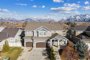 View of front of house with a mountain view, a residential view, driveway, and fence