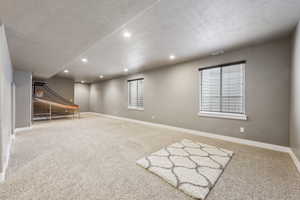 Below grade area with carpet, visible vents, baseboards, recessed lighting, and a textured ceiling