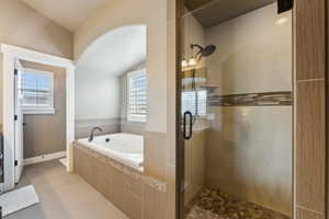 Bathroom featuring tile patterned flooring, baseboards, lofted ceiling, a garden tub, and a stall shower