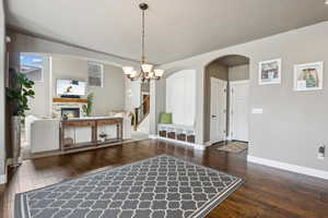 Foyer featuring stairway, baseboards, an inviting chandelier, a fireplace, and wood-type flooring